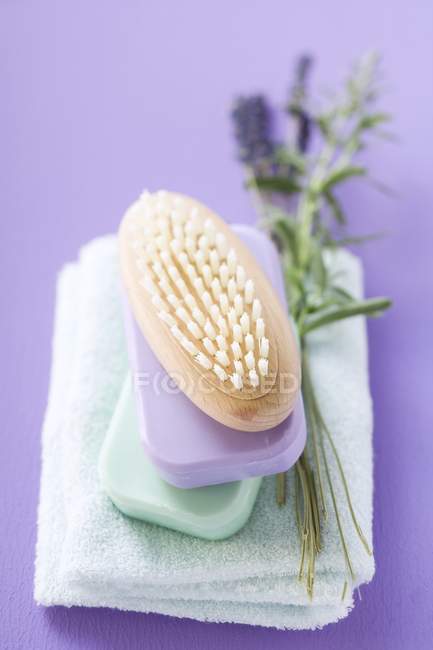 Erhöhte Ansicht von Pinsel und aufgetürmten Stäben farbiger Seife auf Handtuch mit Lavendelzweig — Stockfoto