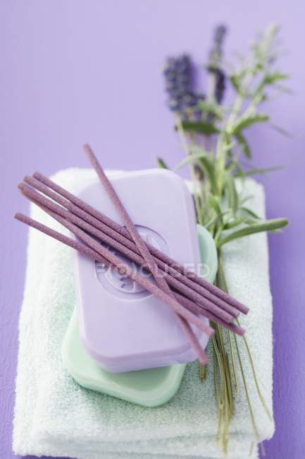 Räucherstäbchen und Seifenstäbchen auf Handtuch mit Lavendelzweigen — Stockfoto