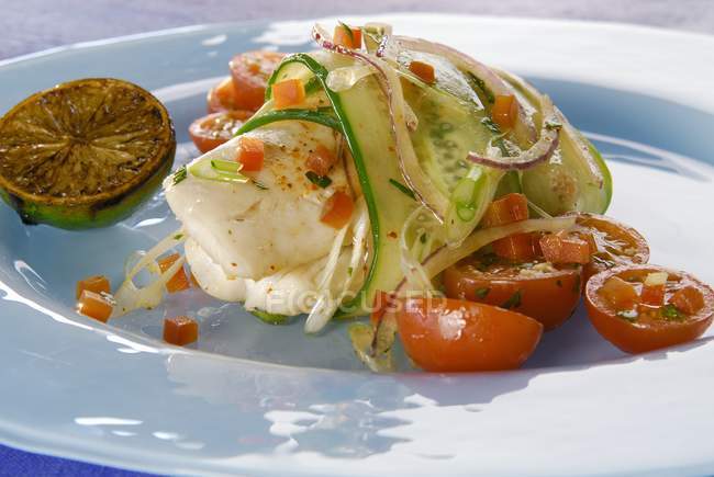 Жареное филе форели с помидорами и огуречным салатом на белой тарелке — стоковое фото