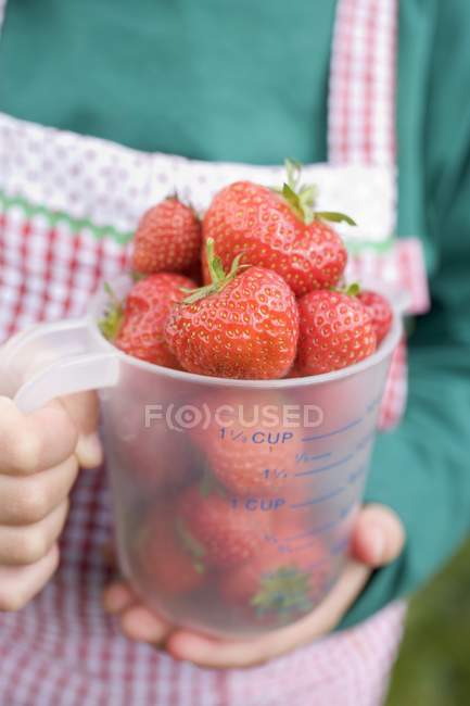 Kind hält Krug mit Erdbeeren — Stockfoto