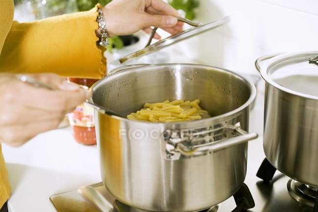 Woman cooking pasta in pot — Stock Photo