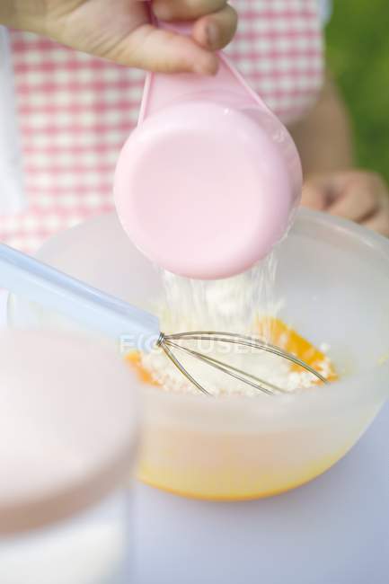 Criança adicionando farinha — Fotografia de Stock