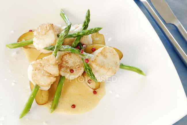 Scallops speared on asparagus with butter sauce in white plate — Stock Photo