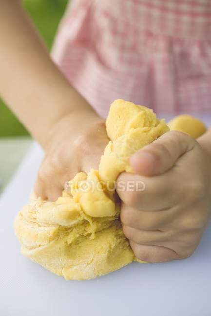 Крупный план детских рук, разминающих тесто — стоковое фото