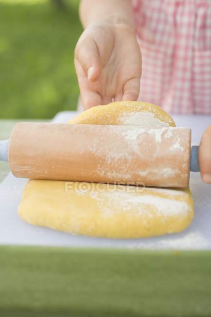 Vue rapprochée de l'enfant déroulant la pâte — Photo de stock