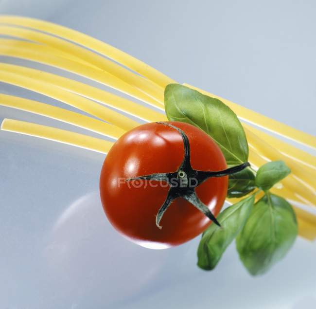 Espaguetis secos con tomate y albahaca - foto de stock