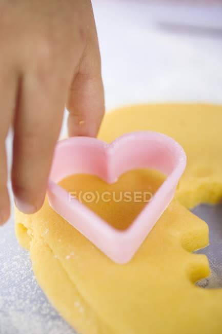 Closeup cropped view of hand cutting out biscuit — Stock Photo