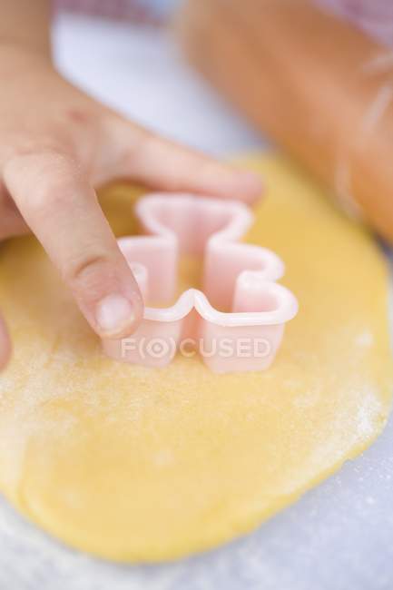 Closeup cropped view of child hand cutting out biscuit — Stock Photo