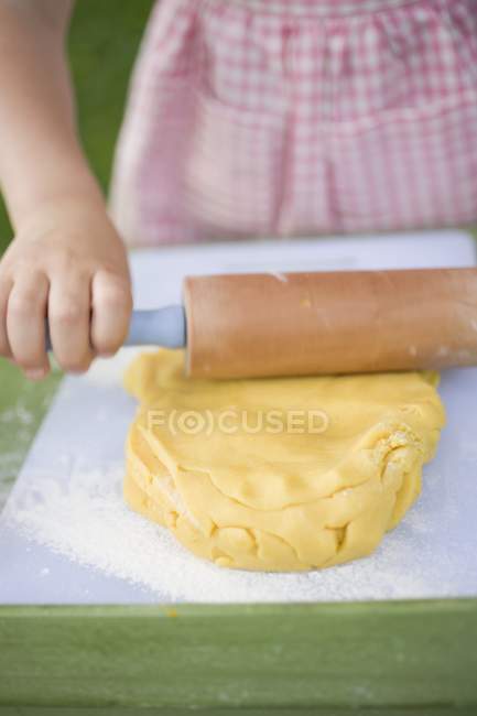 Vue rapprochée de l'enfant déroulant la pâte — Photo de stock