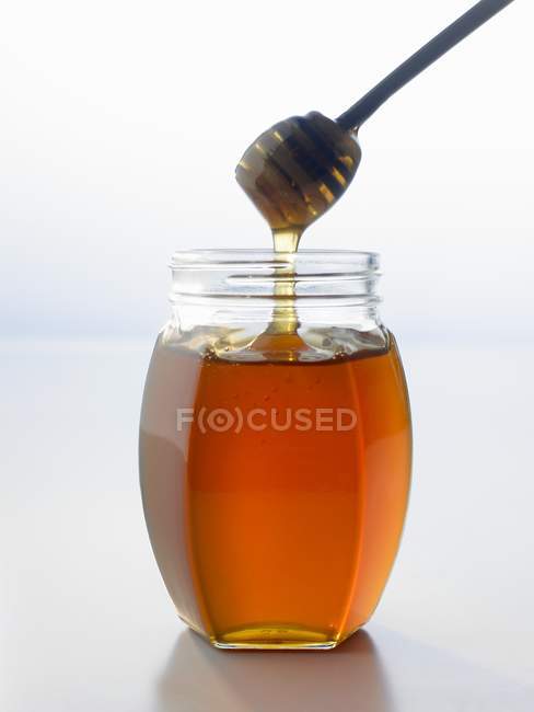 Honey dipper  in jar — Stock Photo