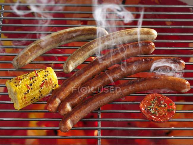 Smoking sausages on grill rack — Stock Photo
