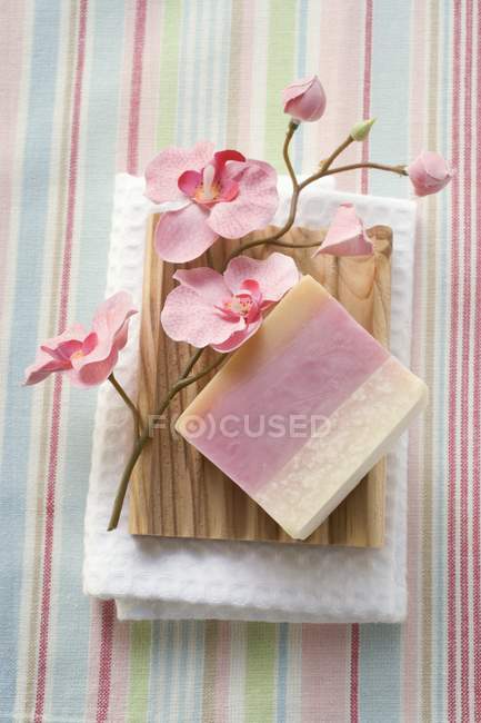 Vista superior de sabão e flores no prato de sabão de madeira na toalha — Fotografia de Stock
