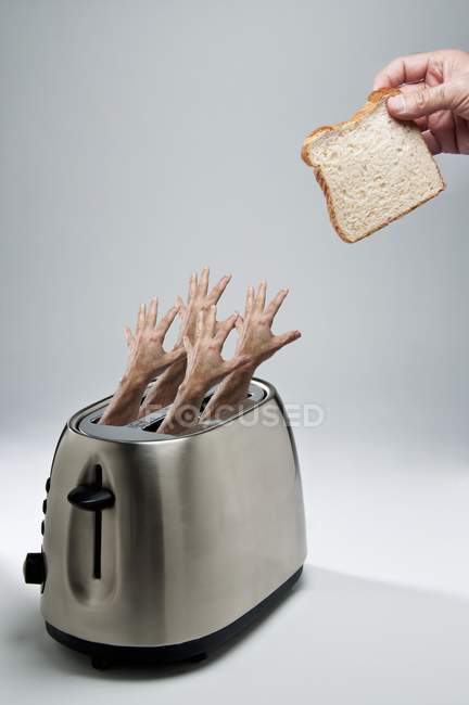 Руки, доходящие до тостера — стоковое фото
