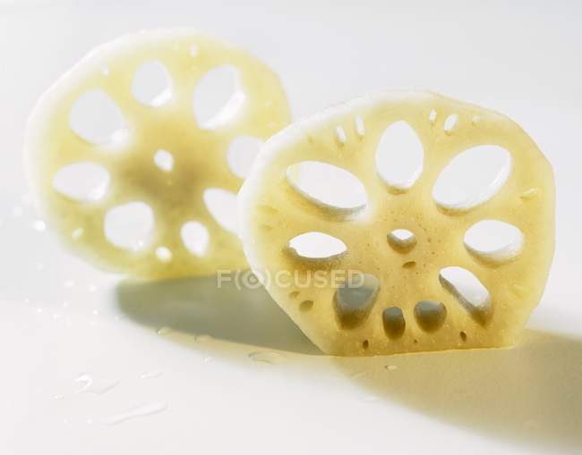 Two slices of lotus root on white surface — Stock Photo
