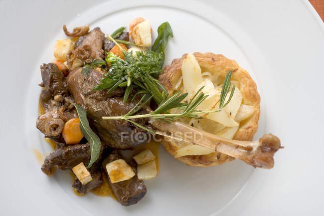 Тушеная гусиная нога с грушей и луковым пирогом на белой тарелке — стоковое фото