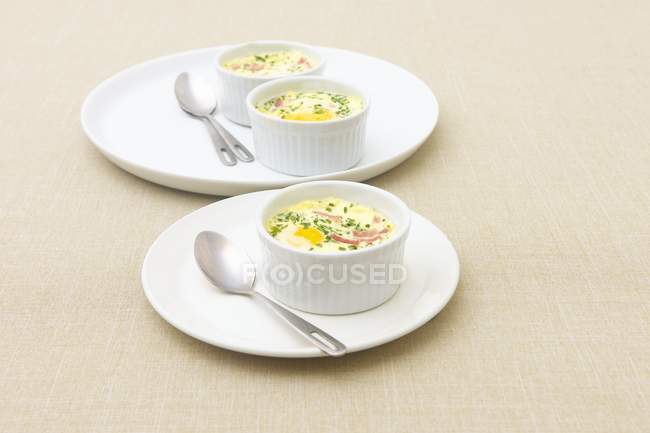 Vista elevada de mini jamón y pasteles de huevo en ramekins blancos - foto de stock