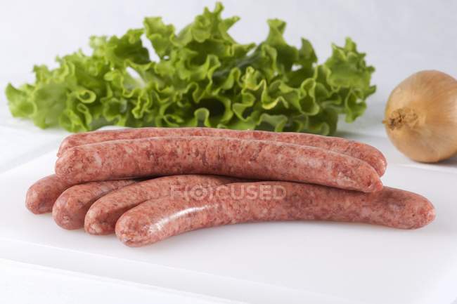 Sausages, mixed salad leaves and onion — Stock Photo