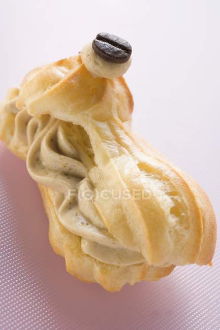 Vista close-up de eclair preenchido com creme de mocha e grãos de café — Fotografia de Stock
