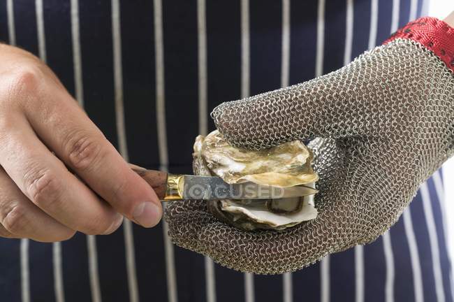 Closeup cropped view of hands shucking oyster — Stock Photo