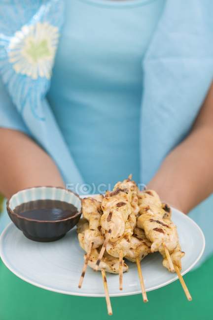 Vista close-up da mulher segurando prato de Satay e molho de soja — Fotografia de Stock
