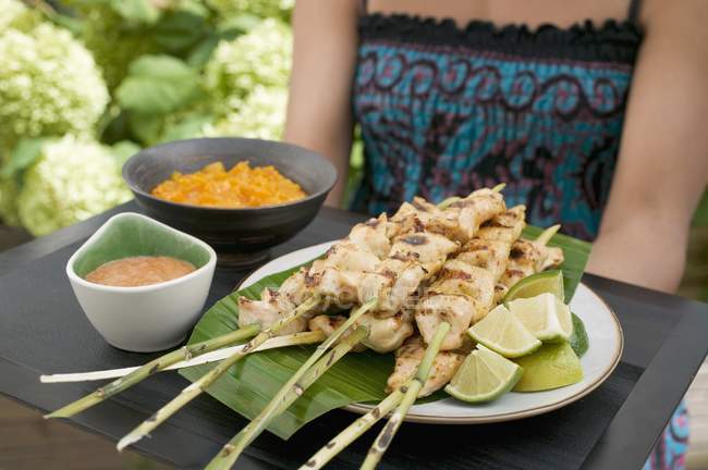 Cropped view of woman holding tray of Satay and dips — Stock Photo