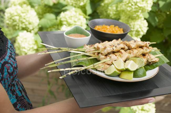 Cropped view of woman holding tray of Satay and dips — Stock Photo