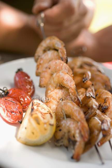 Vista close-up de espetos de camarão grelhados com tomates e limão — Fotografia de Stock