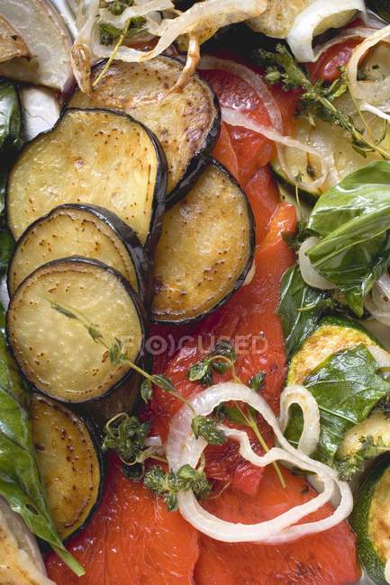 Roasted vegetables with herbs over red wooden surface — Stock Photo