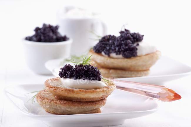 Closeup view of Blinis topped with sour cream and caviar — Stock Photo