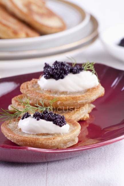 Vista de perto de Blinis coberto com creme de leite e caviar — Fotografia de Stock