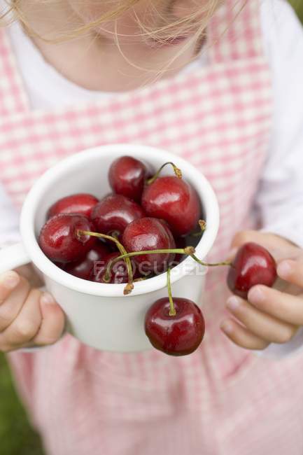 Girl holding pot of cherries — Stock Photo