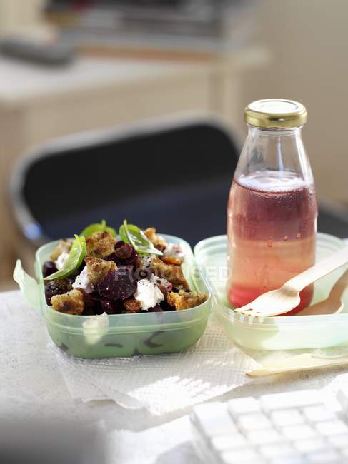 Salad with croutons and bottle of juice — Stock Photo
