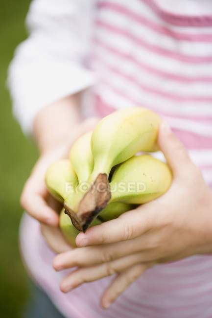 Criança segurando monte de bananas — Fotografia de Stock