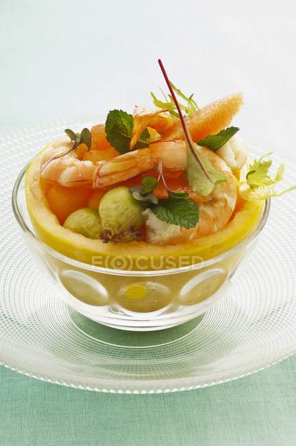 Vista de primer plano de ensalada con melones y camarones en tazón de cristal - foto de stock