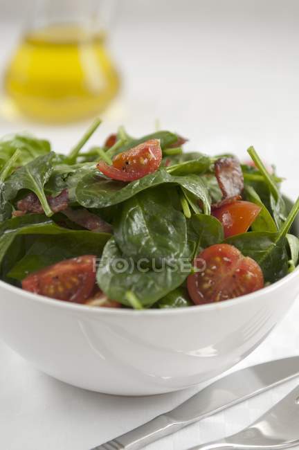 Салат зі шпинату з вишневими помідорами в білій мисці — стокове фото