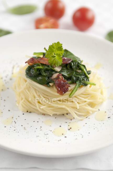 Noodle nest with spinach and dried tomatoes — Stock Photo
