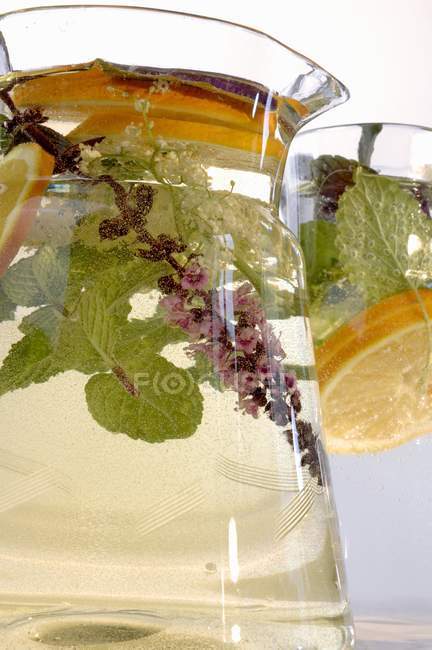 Closeup view of herbal drink with slices of lemon in glass jugs — Stock Photo
