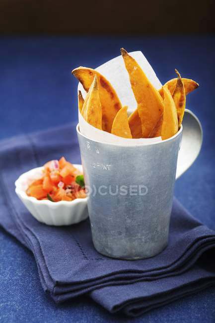 Sweet potato chips with salsa in cup over blue surface — Stock Photo