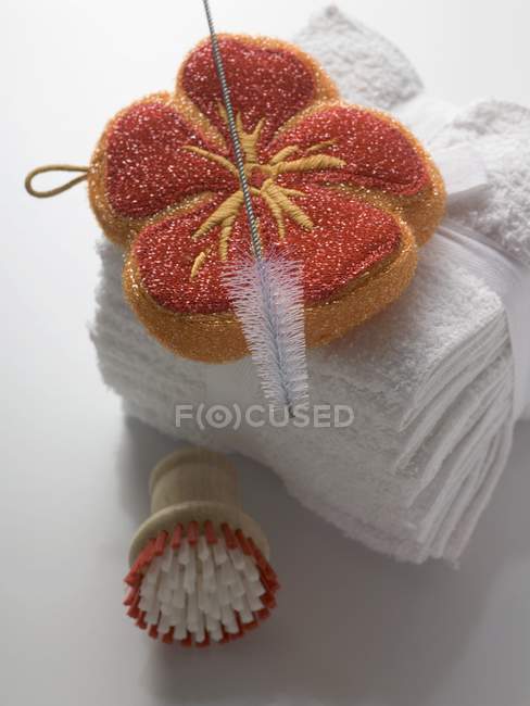 Vista close-up de esponja em forma de flor com escovas e toalhas — Fotografia de Stock