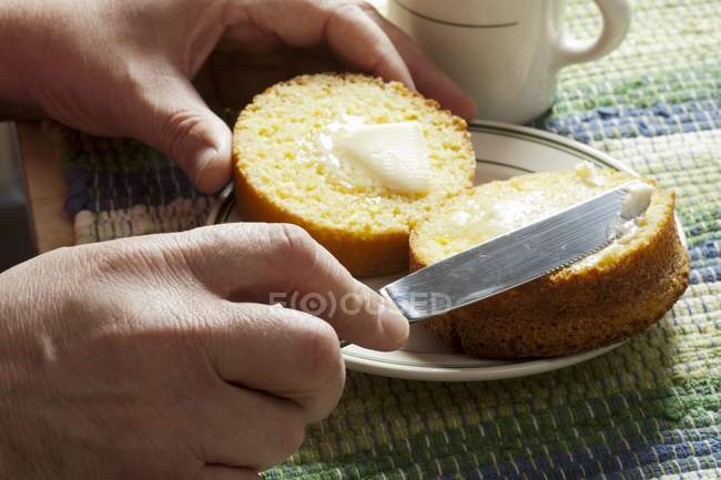 Mão masculina buttering muffin — Fotografia de Stock