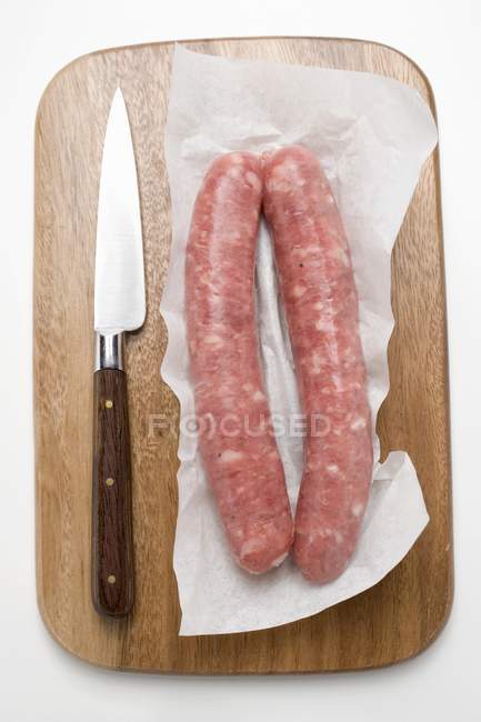 Sausages on paper on chopping board — Stock Photo