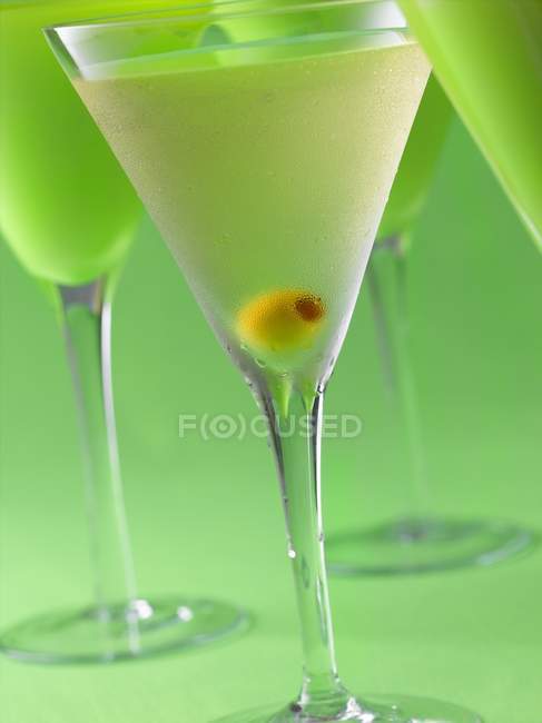Ginebra Martinis con aceitunas sobre fondo verde - foto de stock