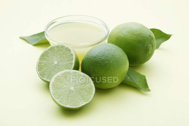 Tigela de suco de limão e limas frescas — Fotografia de Stock
