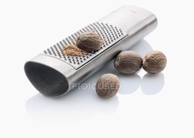 Цельнозерновые мускатные орехи с теркой — стоковое фото