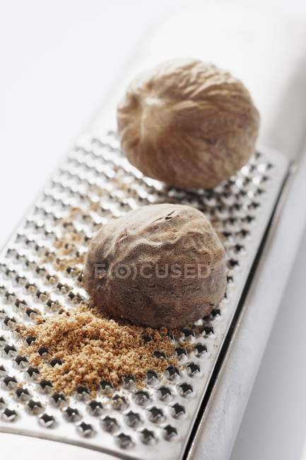Whole nutmegs on grater — Stock Photo