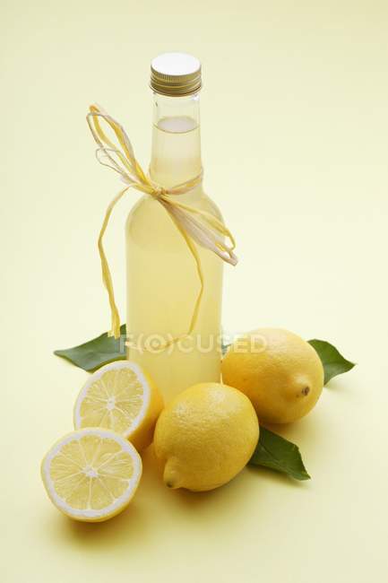 Bottiglia di limonata e limoni freschi — Foto stock