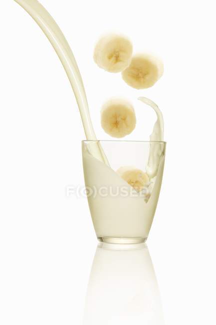 Tranches de bananes tombant dans le lait — Photo de stock