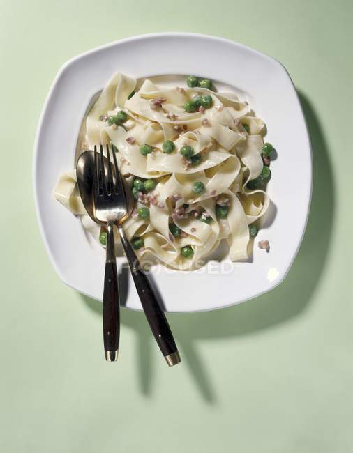 Ribbon pasta with bacon and peas — Stock Photo