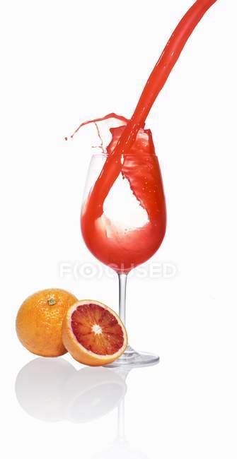 Verter jugo de naranja de sangre en un vaso - foto de stock