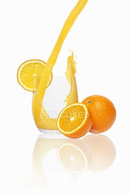 Verter jugo de naranja en un vaso - foto de stock
